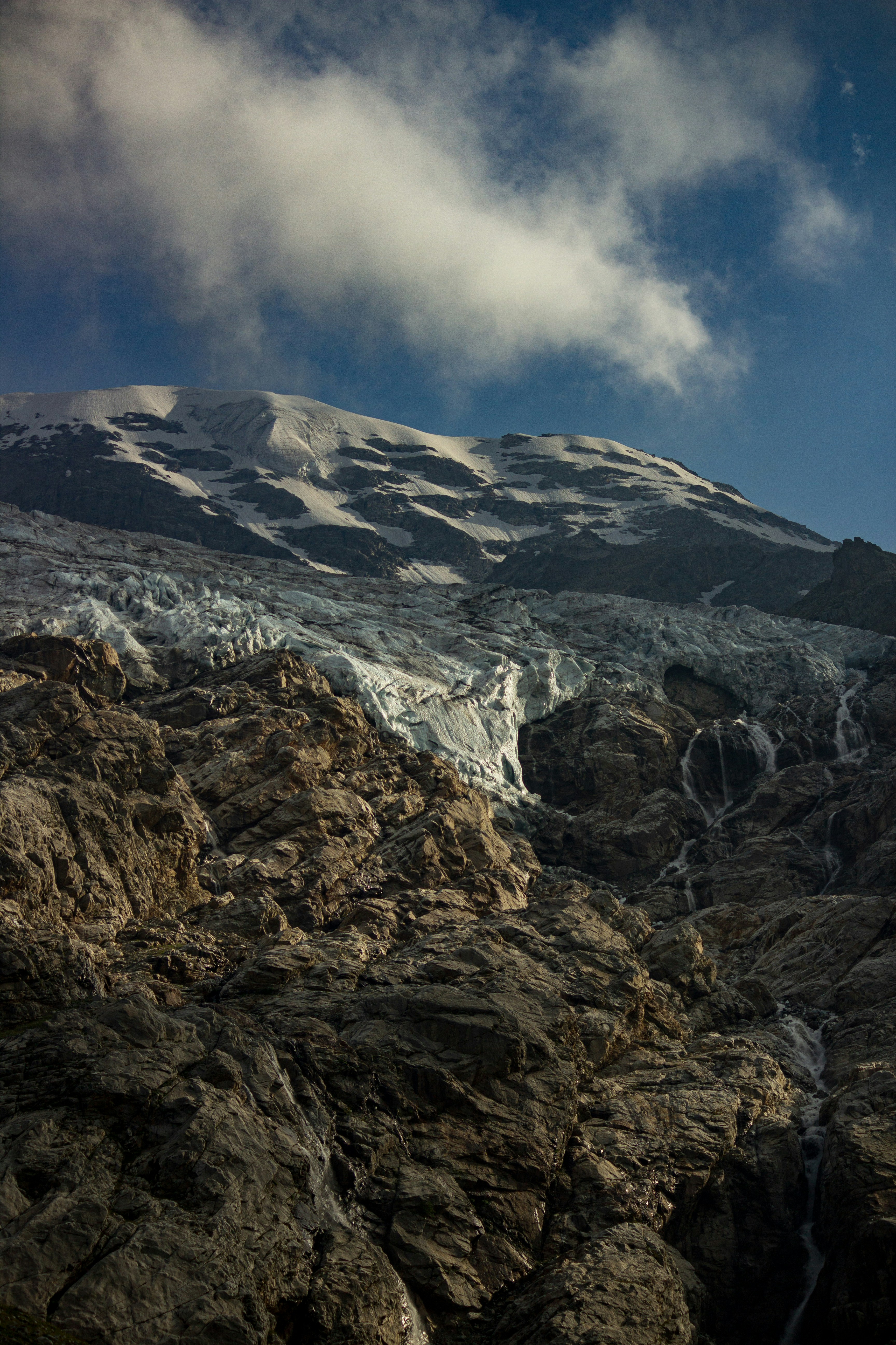 a mountain covered in snow under a cloudy blue sky