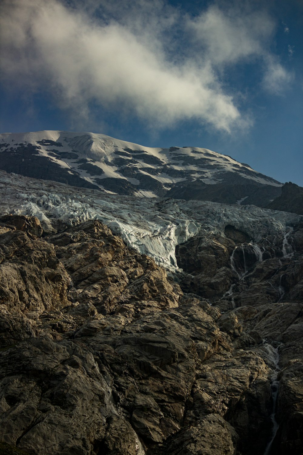 a mountain covered in snow under a cloudy blue sky