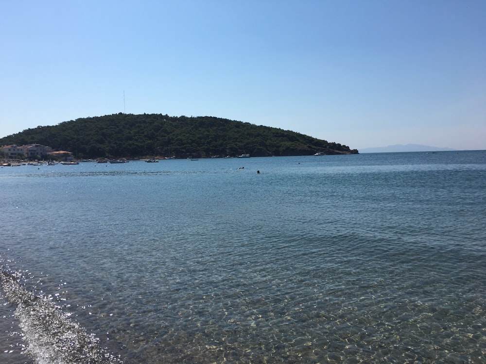 a body of water with a hill in the background