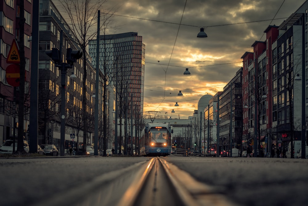 a train traveling down a street next to tall buildings