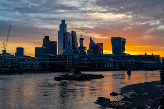 A vibrant city skyline at sunset with new construction sites and cranes in the foreground.