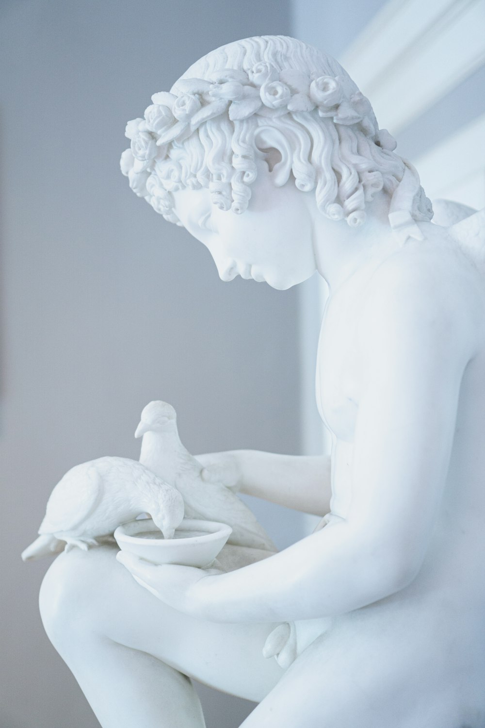 eine Statue eines Jungen mit einem Vogel auf dem Schoß