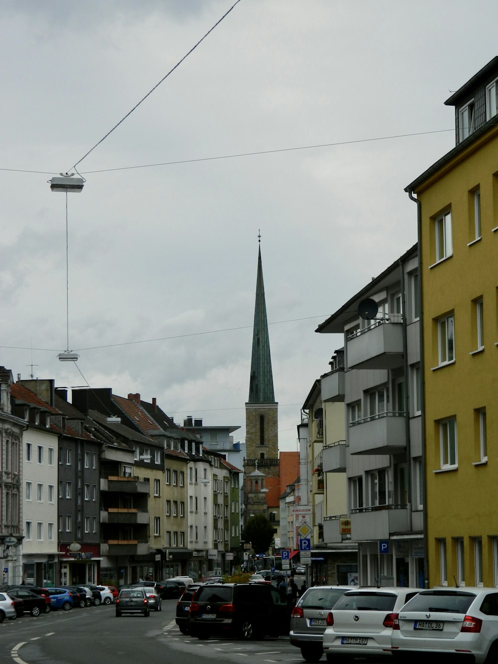 a city street with cars and a church steeple in the background