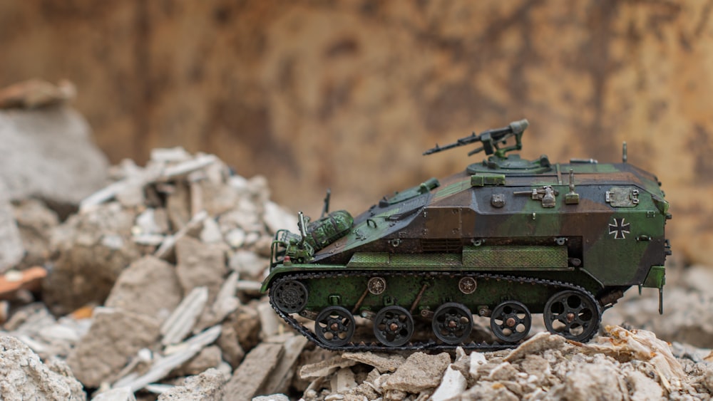 Un tanque del ejército de juguete sentado encima de una pila de escombros