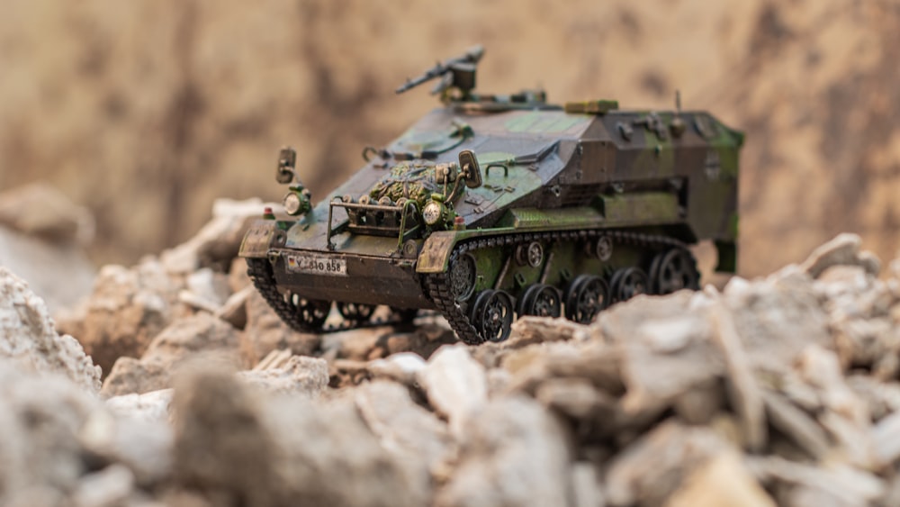 Un vehículo militar de juguete sentado encima de un montón de rocas