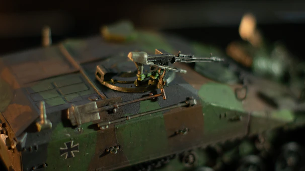 Side view of a camouflaged tank with digital HUD elements projected around it.