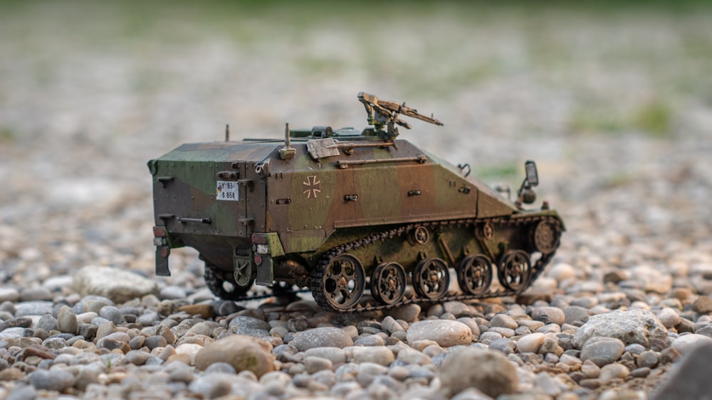 a toy army vehicle sitting on top of a gravel field