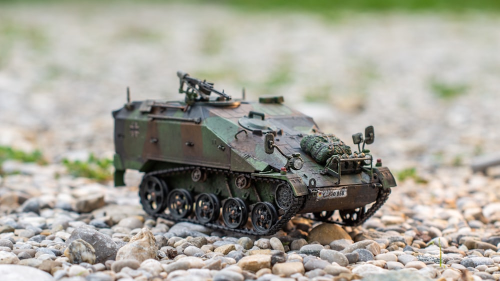 Un tanque del ejército de juguete sentado en la parte superior de un campo de grava