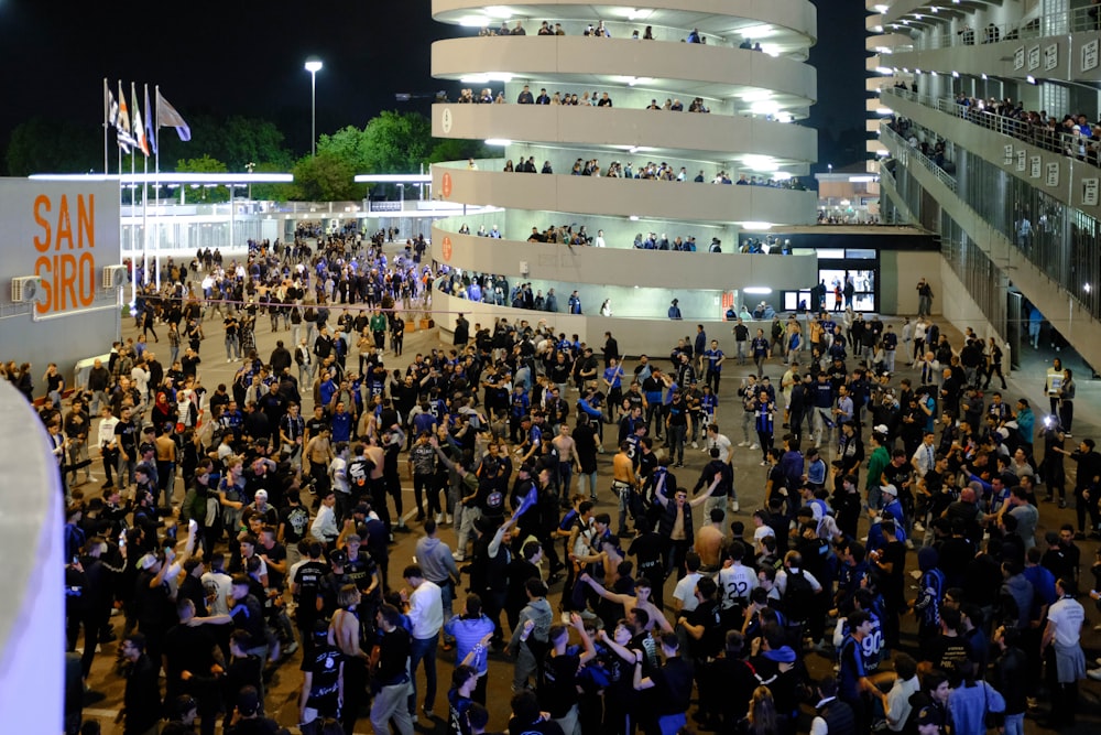 uma multidão de pessoas em pé ao redor de um prédio à noite
