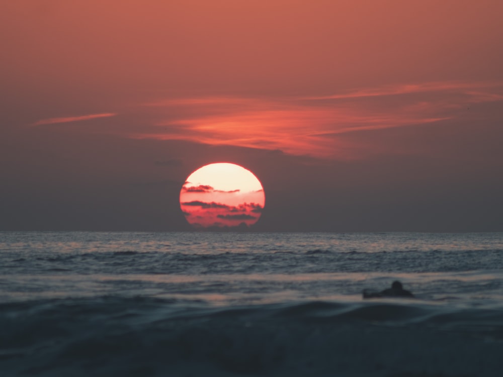 El sol se está poniendo sobre el océano con un bote en el agua