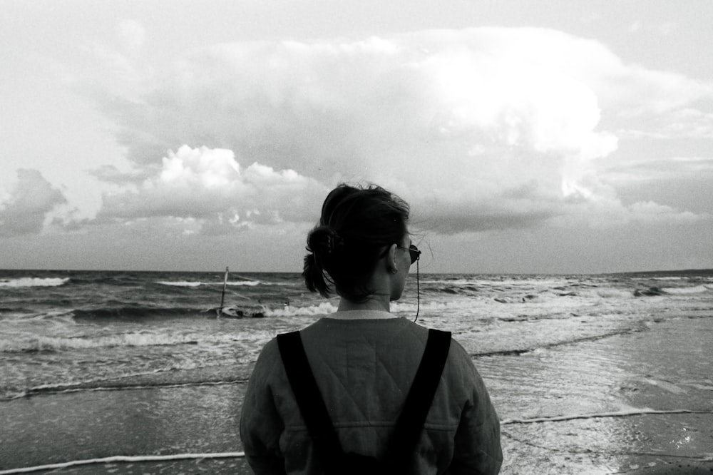 a woman standing on a beach next to the ocean