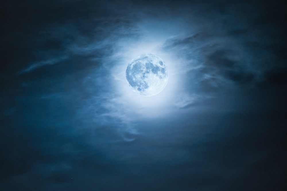 uma lua cheia é vista através das nuvens