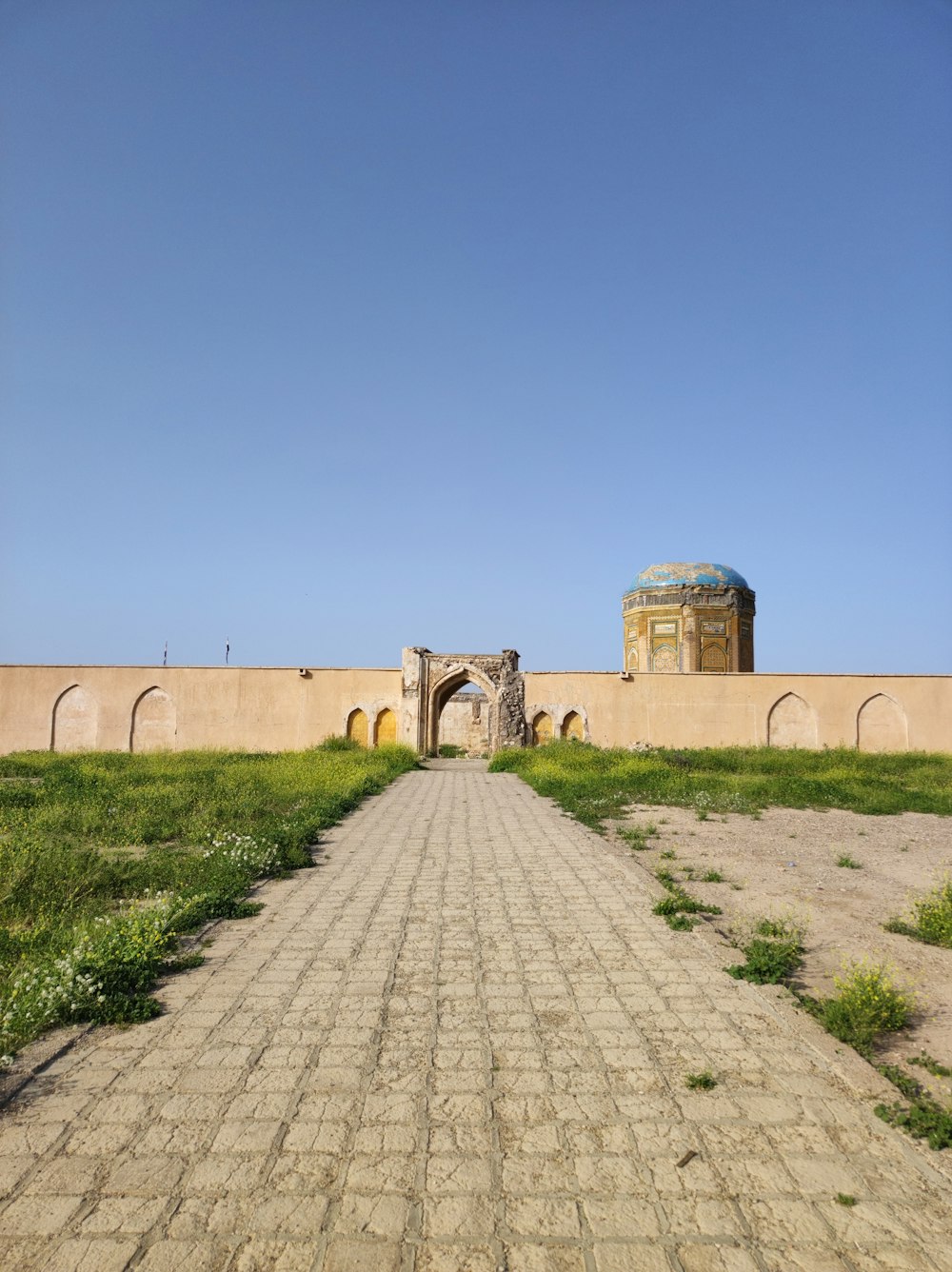 a stone walkway leading to a building with a dome in the background