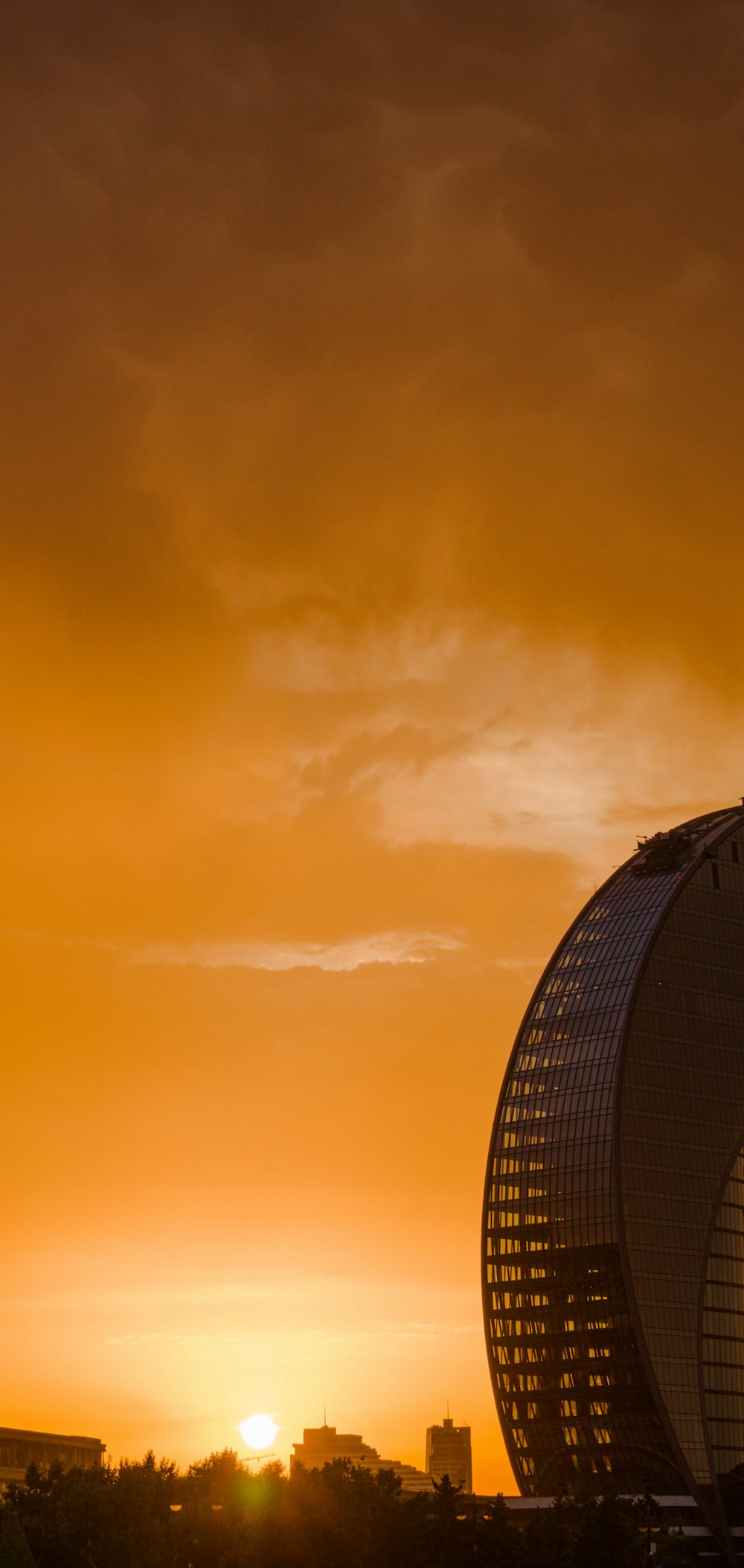 the sun is setting behind a tall building