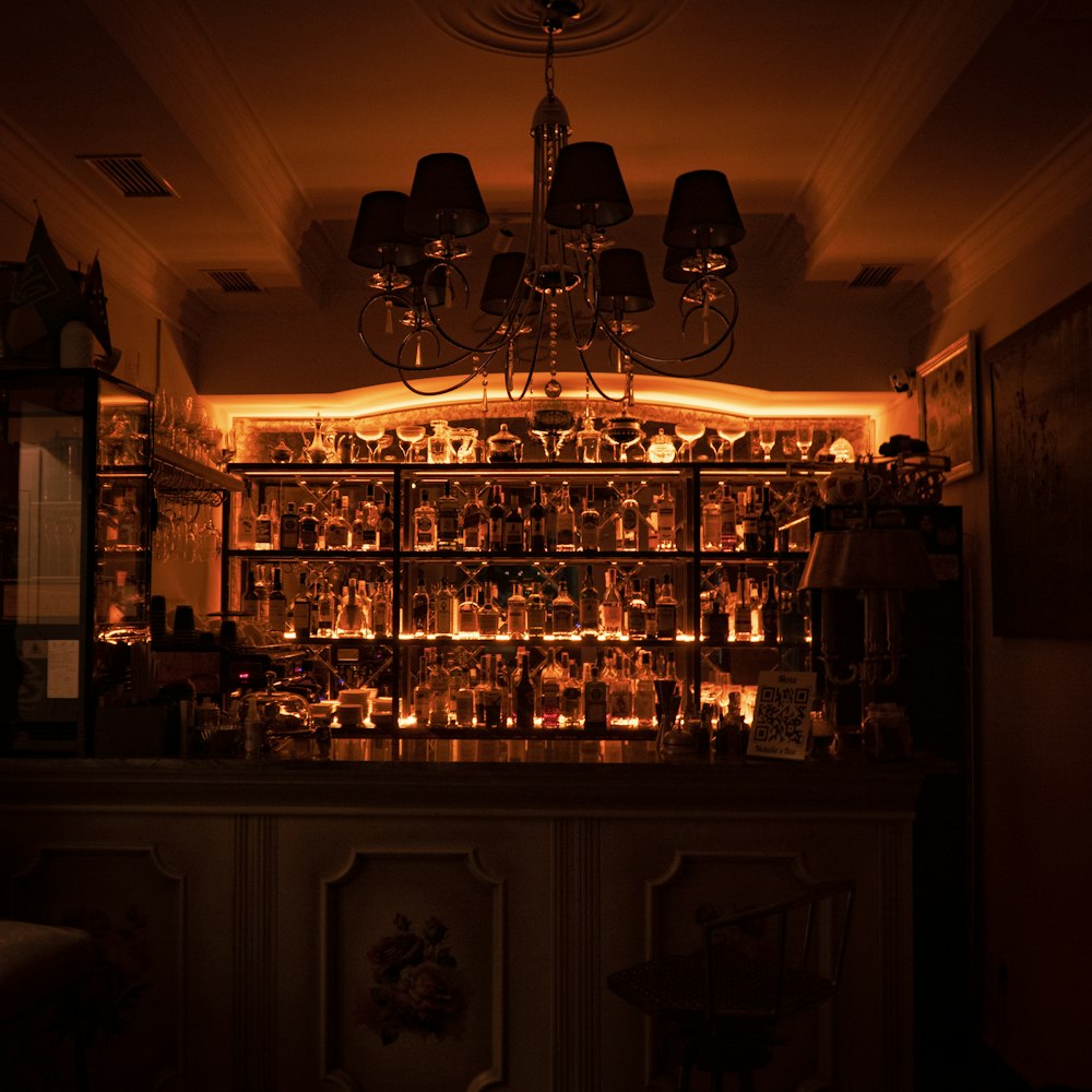 a dimly lit bar with a chandelier hanging from the ceiling