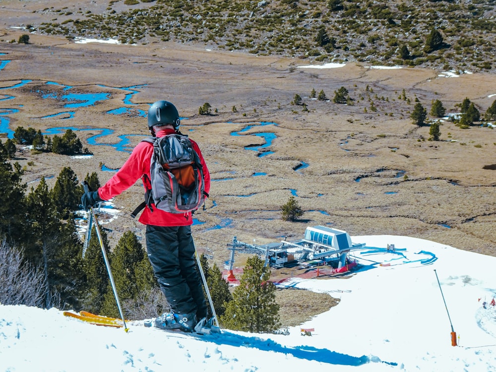 Un hombre parado en la cima de una ladera cubierta de nieve