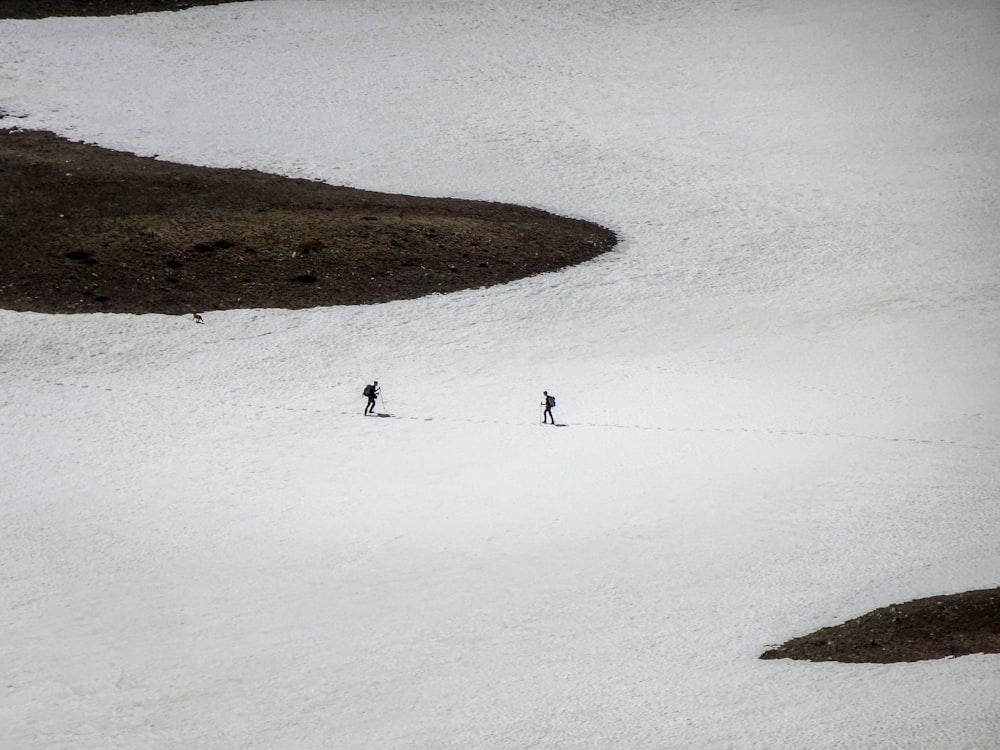 Un par de personas montando esquís por una pendiente cubierta de nieve