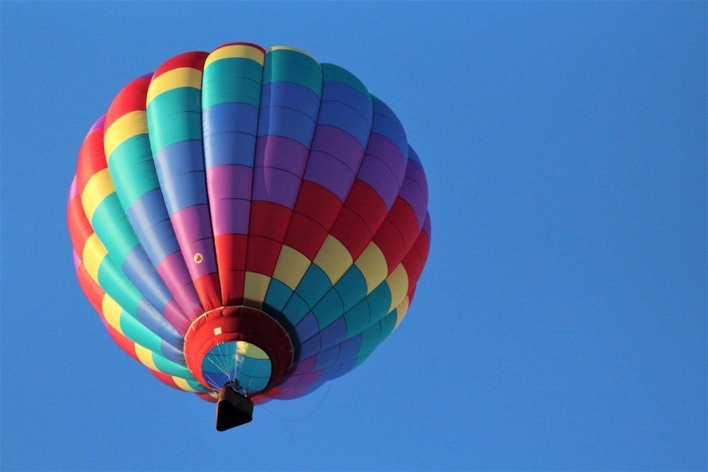 Ein bunter Heißluftballon, der durch einen blauen Himmel fliegt