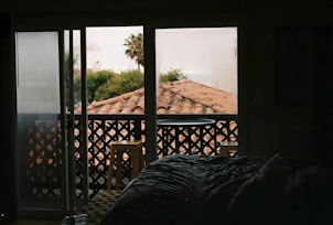 Cozy hotel room with warm lighting and a comfortable bed near a window overlooking a tropical garden.