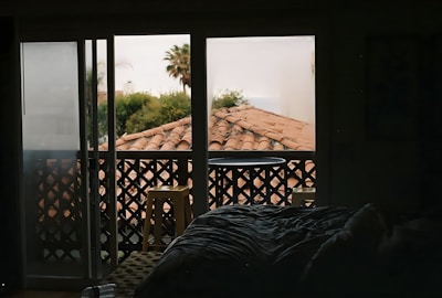 A cozy boutique hotel room with warm lighting and a view of palm trees swaying by the sea.