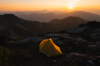 Camp setup with cozy tents nestled among rocky terrain at dusk.