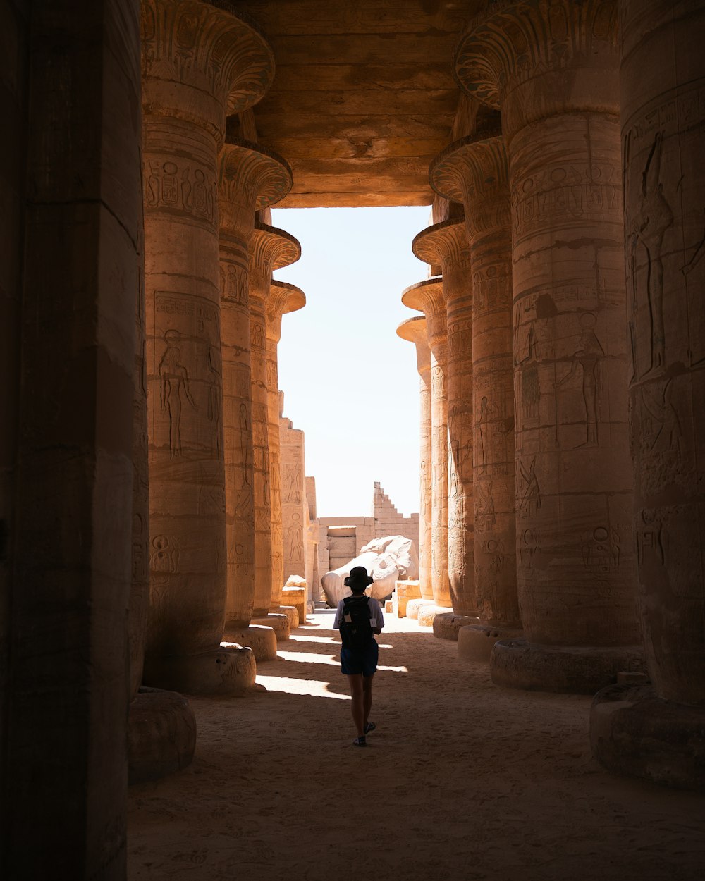 a woman in a black dress is walking through an egyptian temple