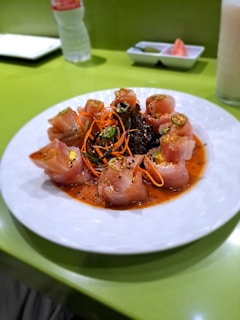 Sleek black plate showcasing a modern sushi roll topped with thinly sliced jalapeño and drizzled with spicy mayo