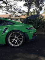A compact economy car parked near a cozy suburban home with greenery around.