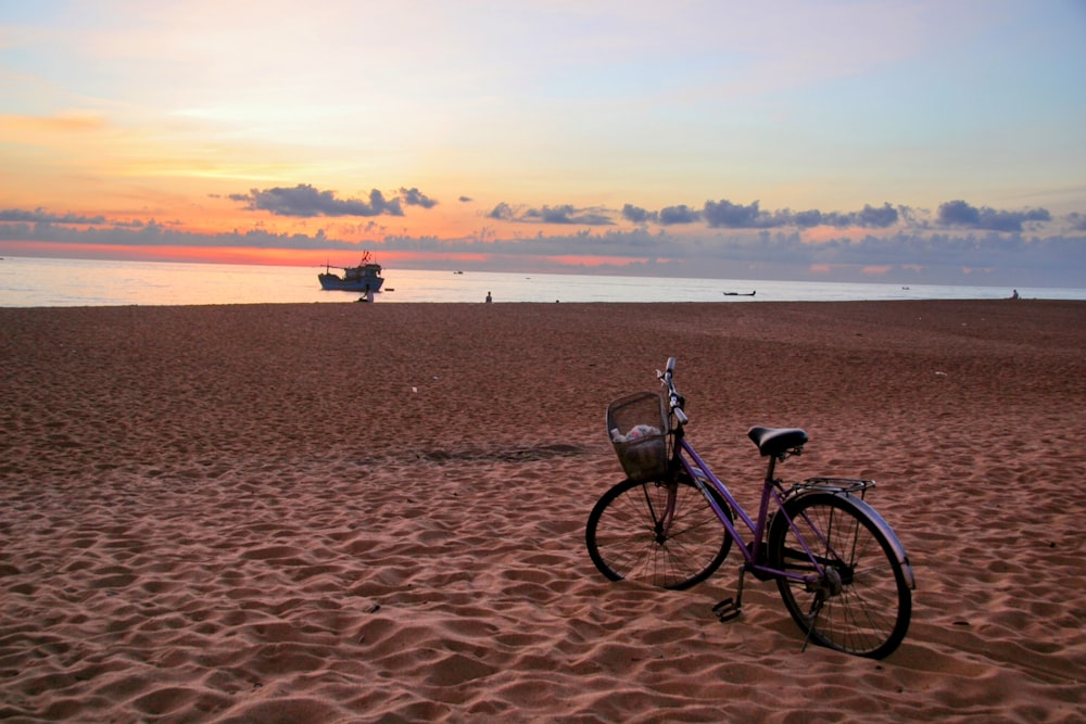 a bike parked on a beach next to the ocean