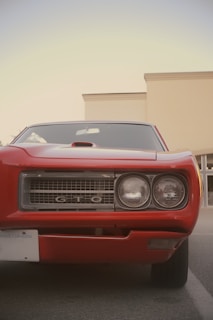 a red car parked in a parking lot next to a building