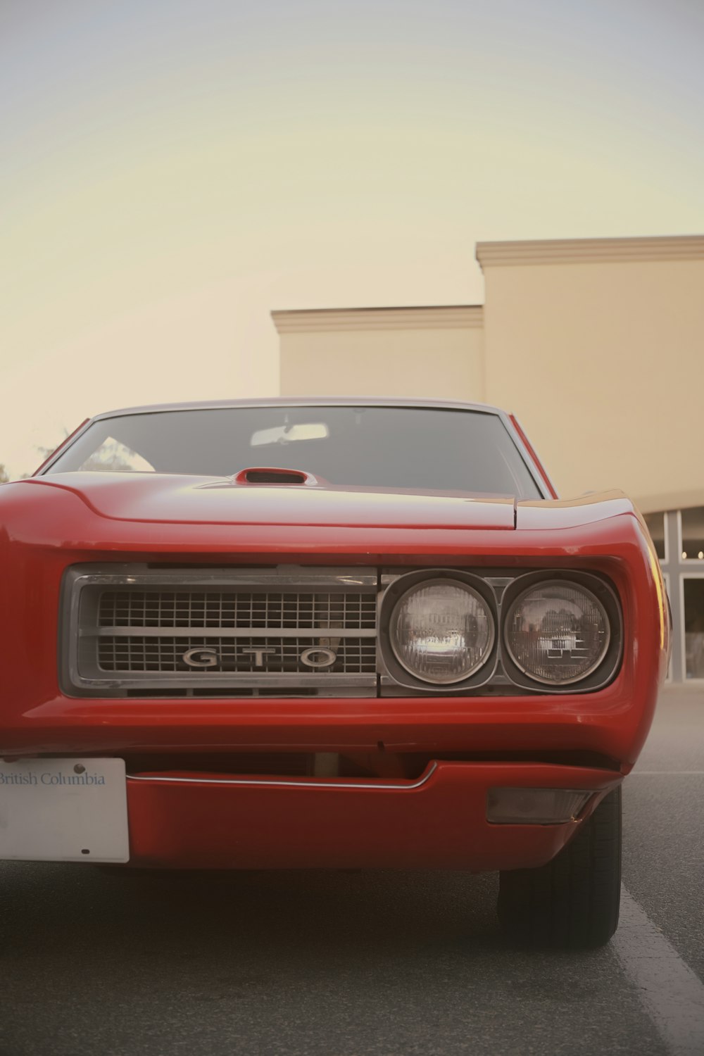 a red car parked in a parking lot next to a building