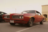 Model wearing a red muscle car tee standing beside a classic Dodge Charger.