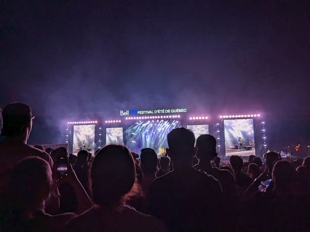 A vibrant crowd enjoying a live concert streamed on a large screen outdoors.