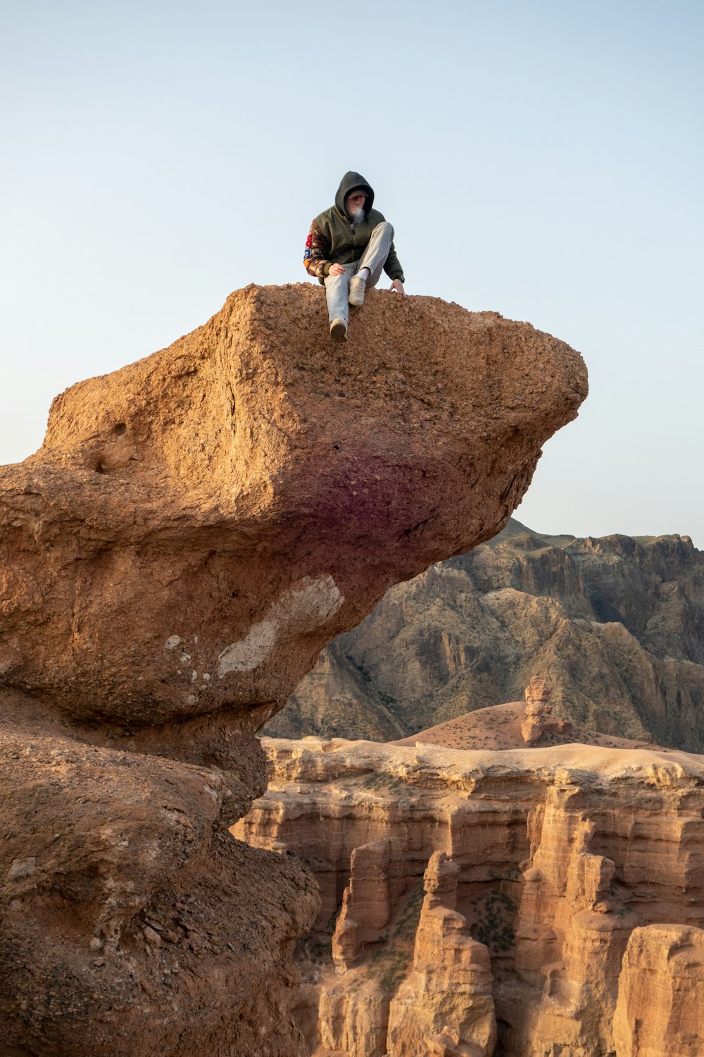 a man sitting on top of a large rock