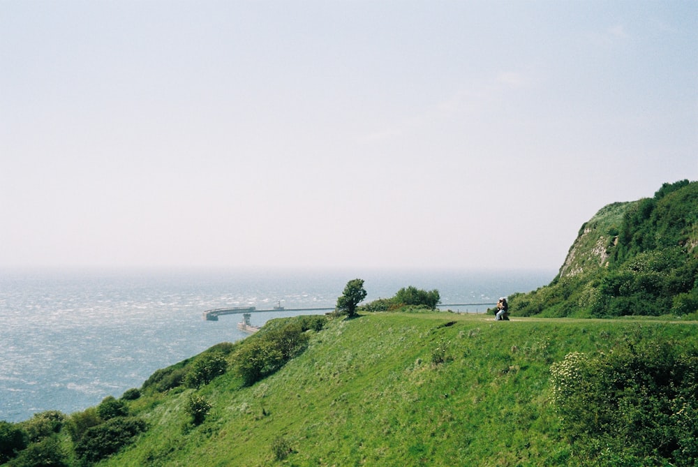 a couple of people riding horses down a hill next to the ocean