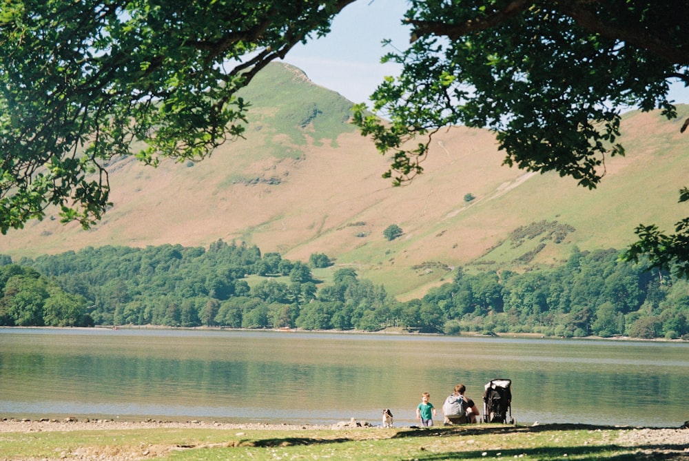 a group of people sitting on a bench next to a lake