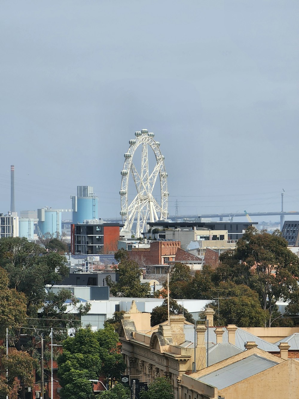 a ferris wheel in the distance with buildings in the foreground