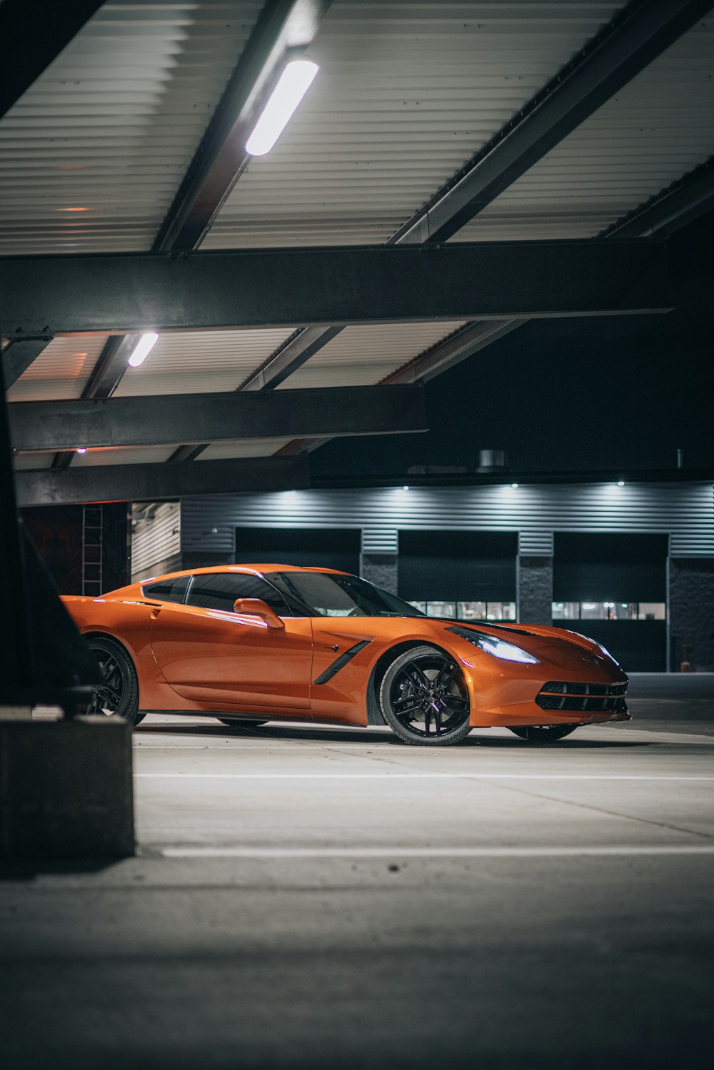 an orange sports car parked in a parking garage