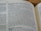 A close-up view of an open book displaying text from a religious scripture. The text is in black font on white pages. The page heading 'Old Testament' is visible and the verses appear to be discussing themes of gathering and restoration.