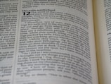 A close-up image of a book page showing text in English, discussing themes related to exile and the word of the Lord. The text includes a passage from the Bible, with some words in bold. The page appears slightly angled, and the focus is primarily on the left side.