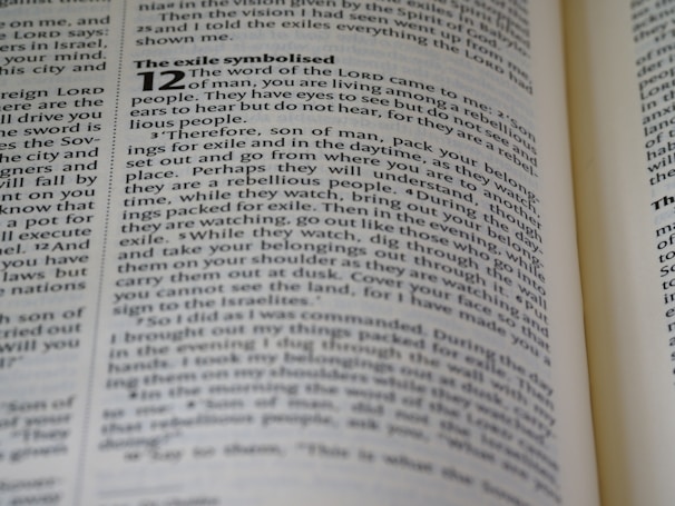 A close-up image of a book page showing text in English, discussing themes related to exile and the word of the Lord. The text includes a passage from the Bible, with some words in bold. The page appears slightly angled, and the focus is primarily on the left side.