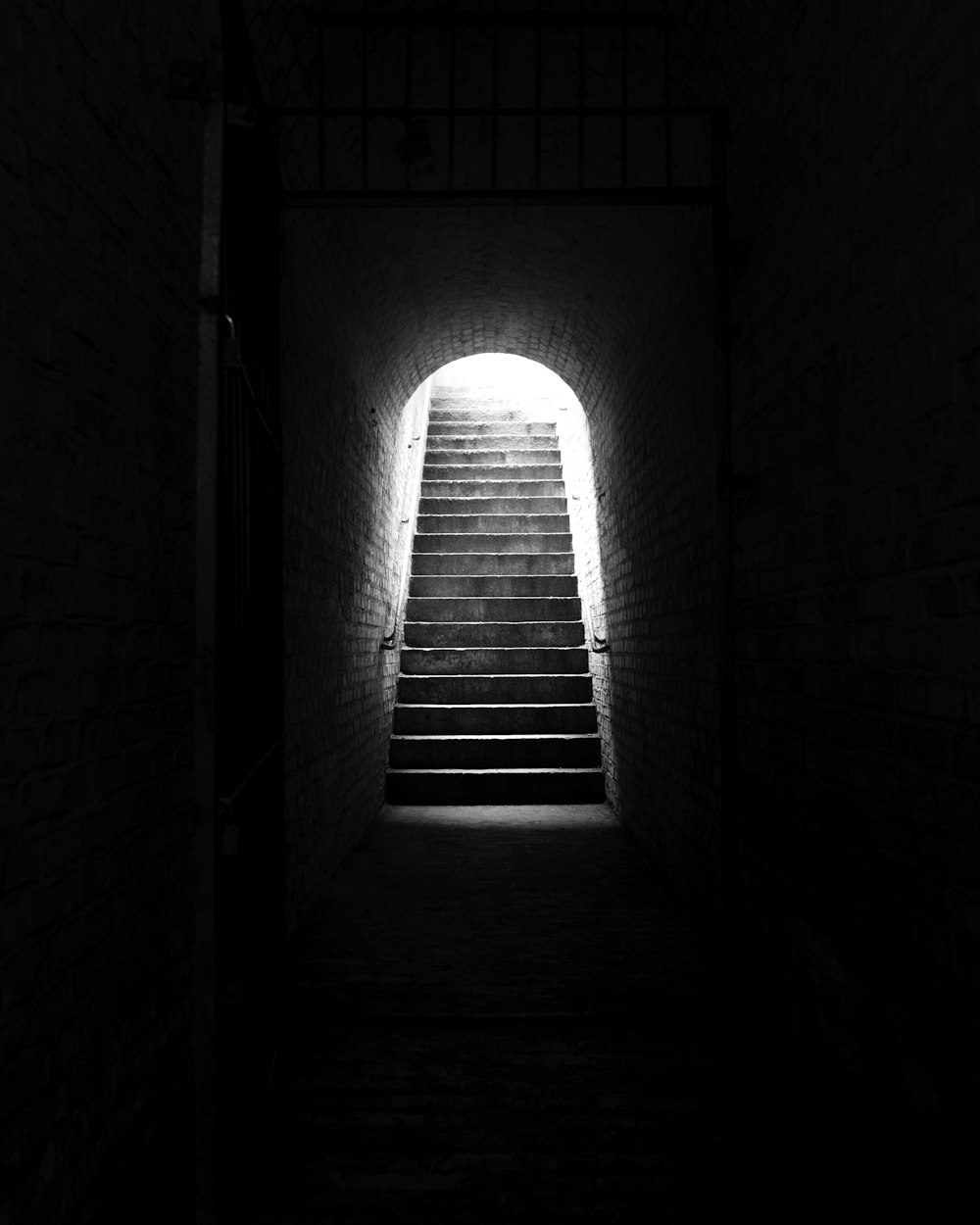 a dark tunnel with stairs leading up to the light