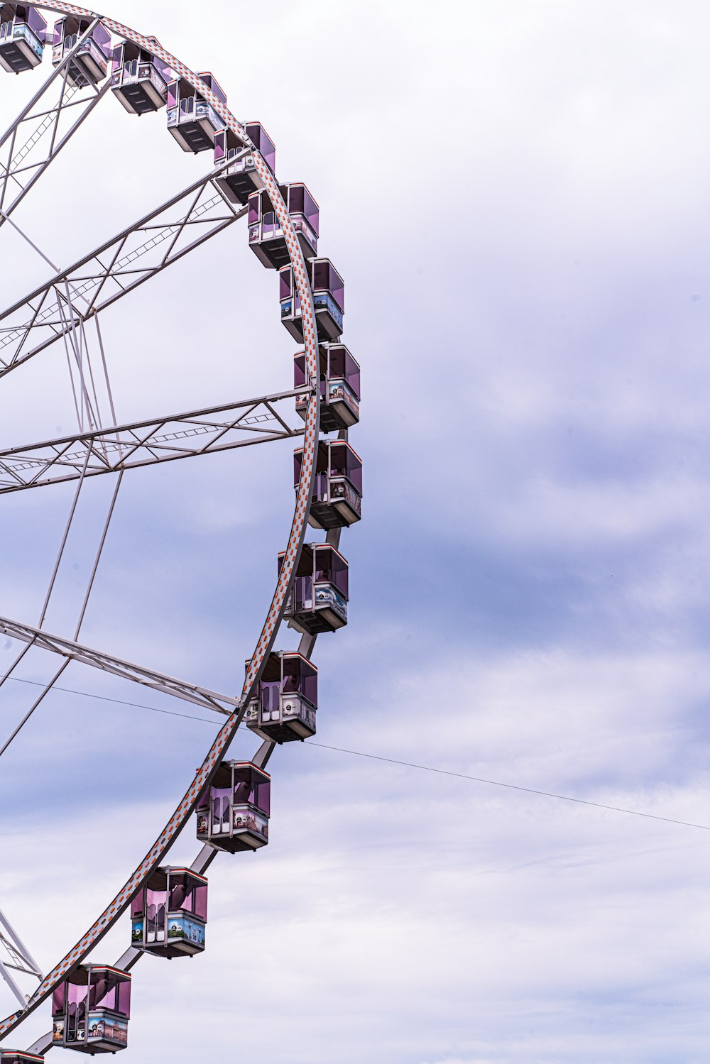 a ferris wheel with purple seats on a cloudy day