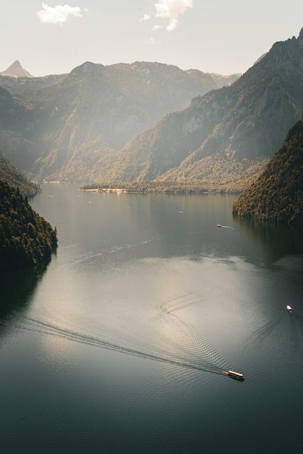 a boat is in the middle of a lake surrounded by mountains