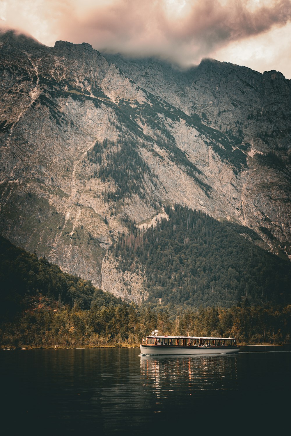 a boat floating on top of a lake next to a mountain