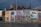 A building façade is painted with a vibrant mural depicting scenes of coastal life. The artwork features fishermen, boats, and a seaside town, with vivid colors and intricate details. The building's architecture is traditional with multiple chimneys and a rusty corrugated metal roof.