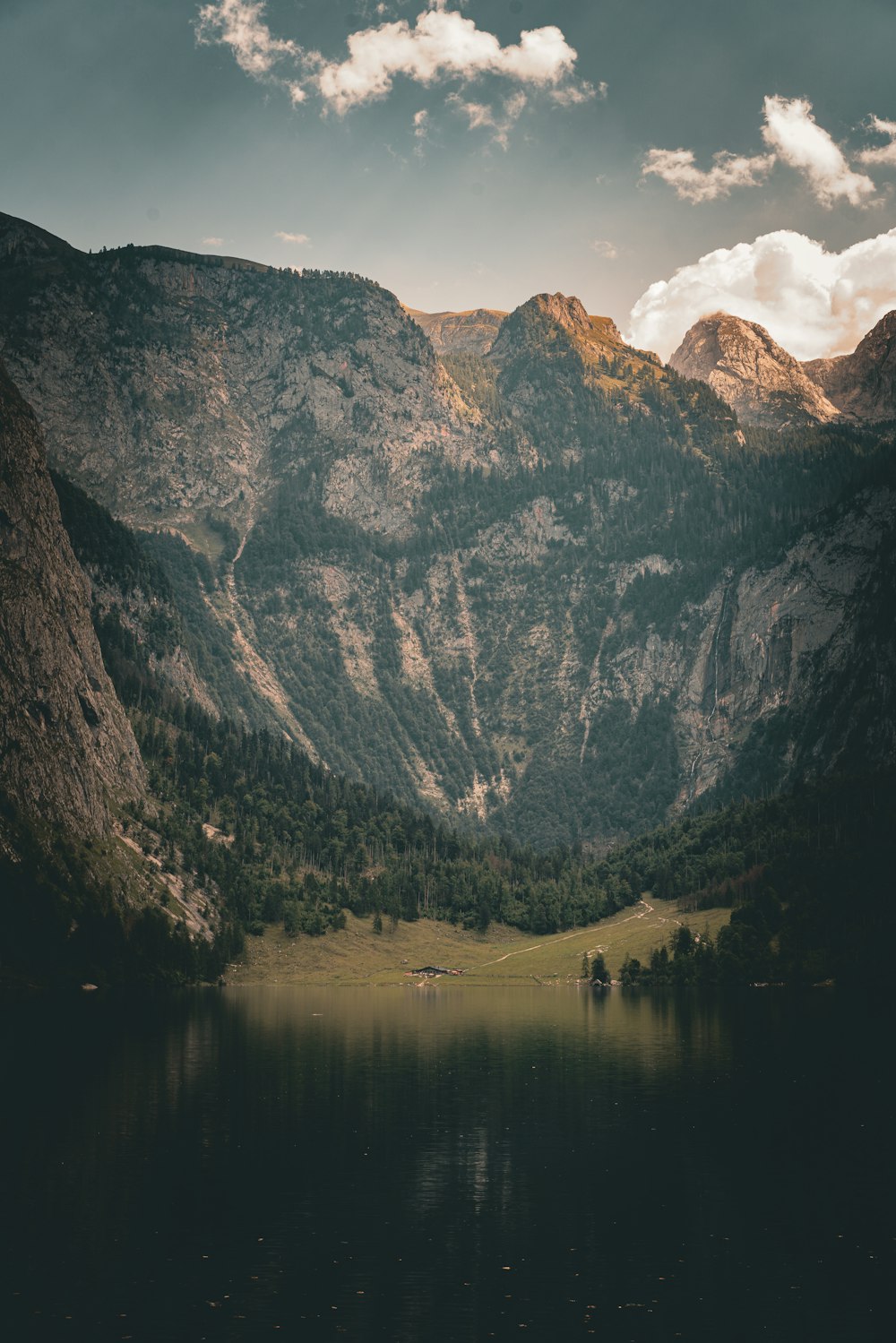 a lake surrounded by mountains under a cloudy sky