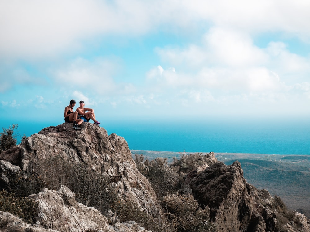 um casal de pessoas sentadas no topo de uma montanha