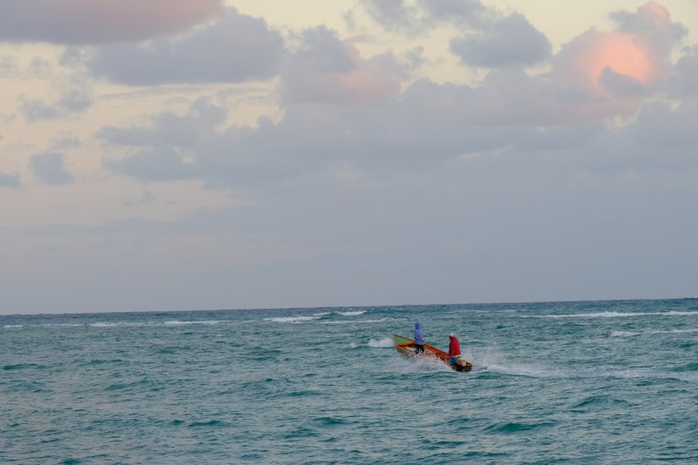 a couple of people riding on top of a boat in the ocean