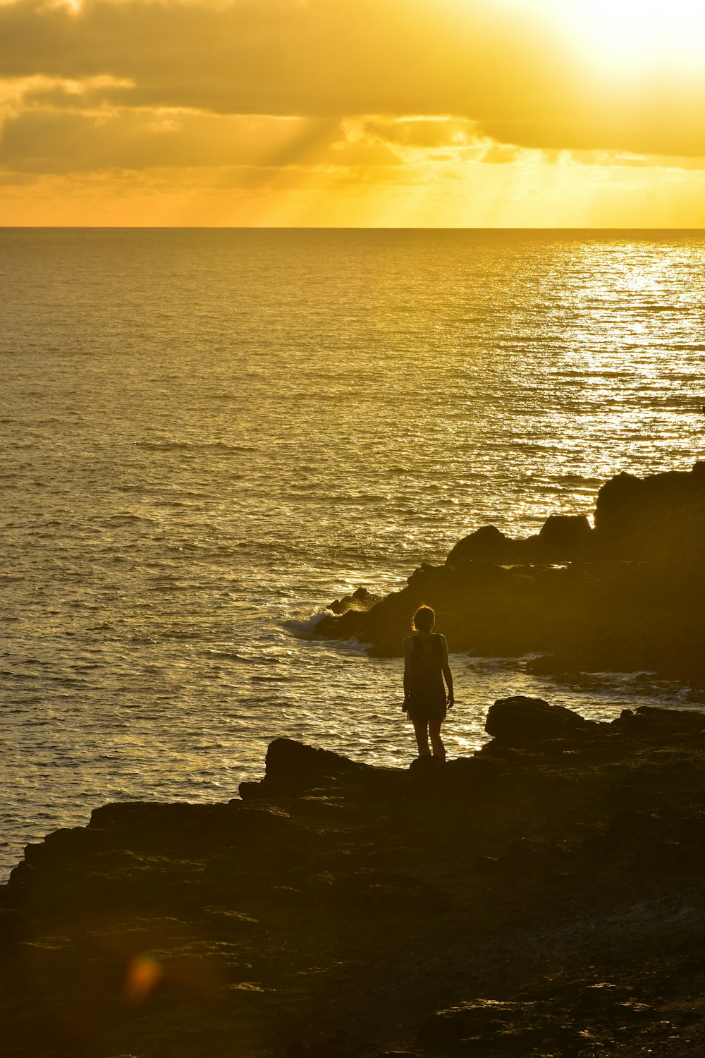 a person standing on a rocky cliff near the ocean